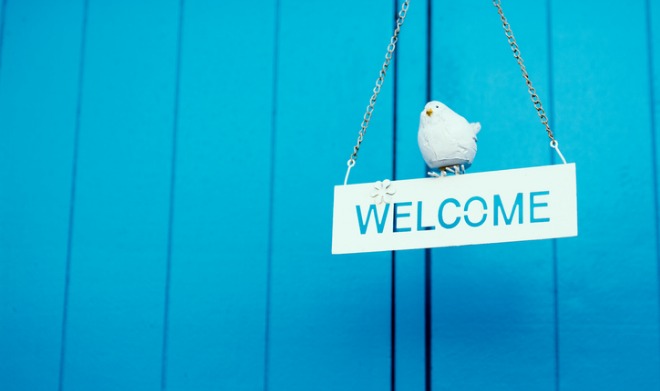 rustic-wood-welcome-sign-hanging-on-blue-background-picture-id497939012