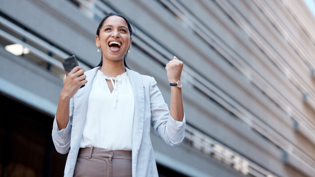 Phone, success celebration and woman in city after winning, deal or receiving startup funding. Wow, winner and Indian female excited, victory or celebrating financial goals, mission or sales targets.
