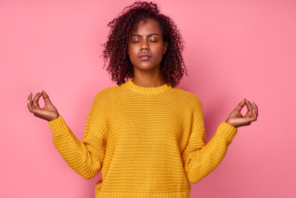 Calm dark-skinned woman relaxing meditation, no stress-free relief at work concept, mindful peaceful young business woman or student practicing breathing yoga exercises, isolated over pink background
